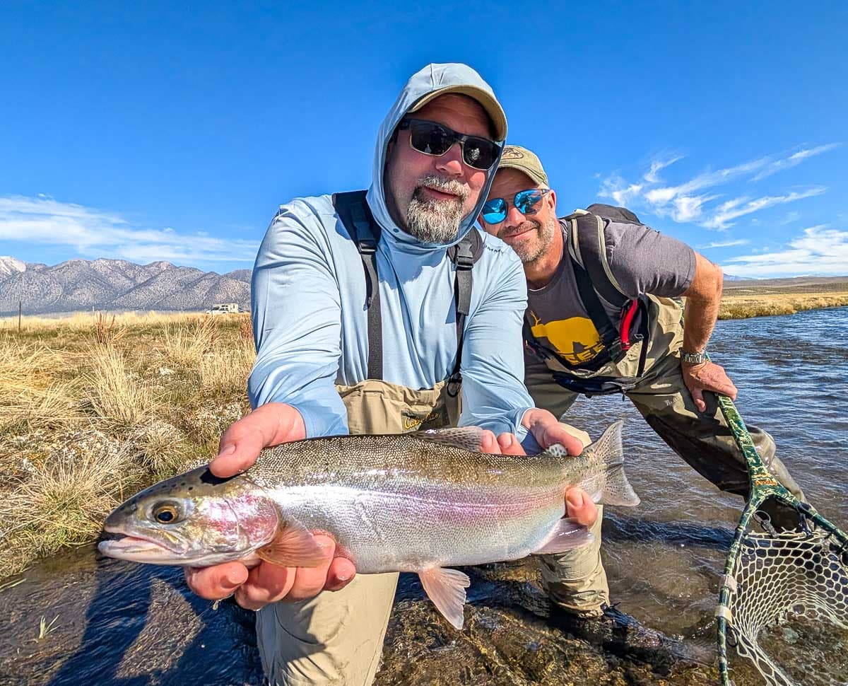 A fly fisheman holding a large rainbow trout on the Upper Owens River near Mammoth Lakes, CA