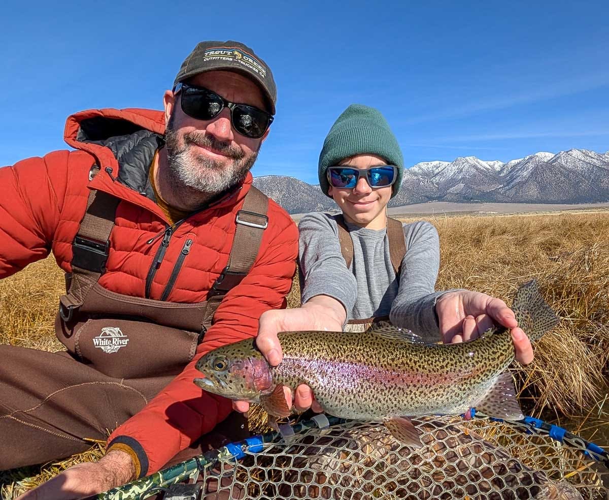 A fly fisheman holding a large rainbow trout on the Upper Owens River near Mammoth Lakes, CA