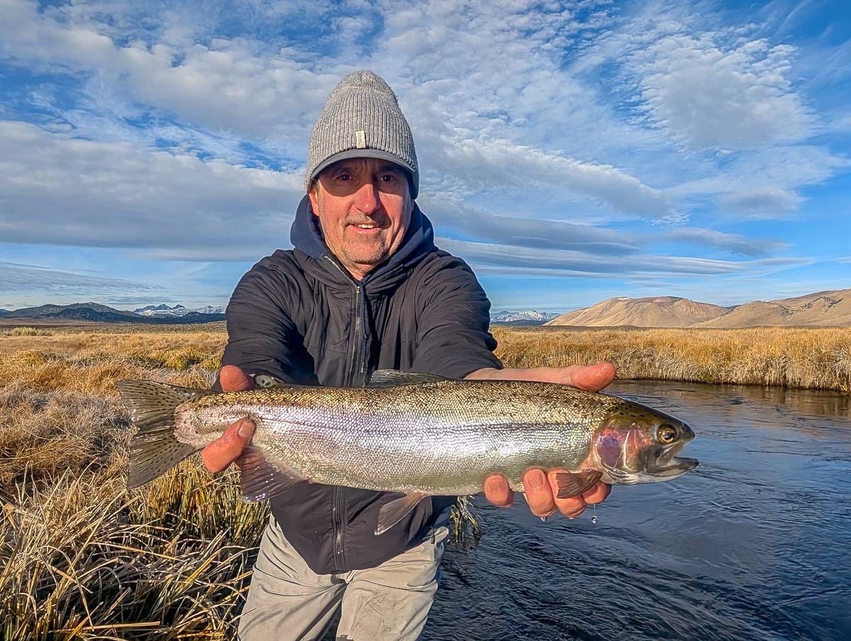 A fly fisheman holding a large rainbow trout on the Upper Owens River near Mammoth Lakes, CA
