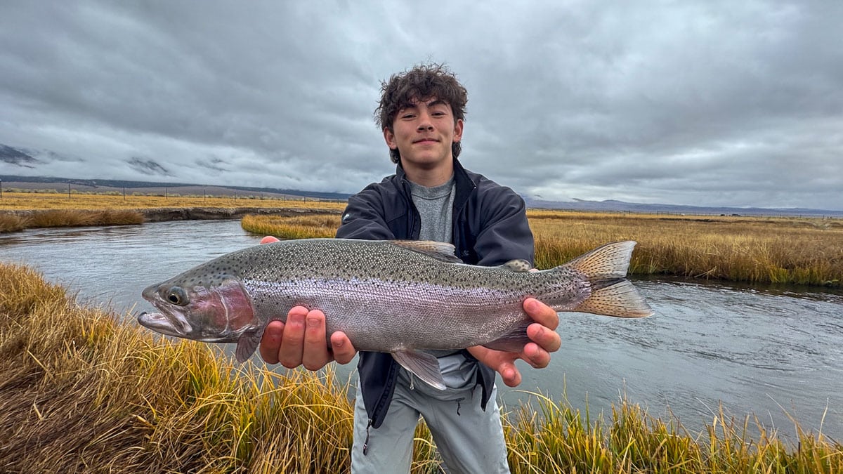 A fly fisheman holding a large rainbow trout on the Upper Owens River near Mammoth Lakes, CA