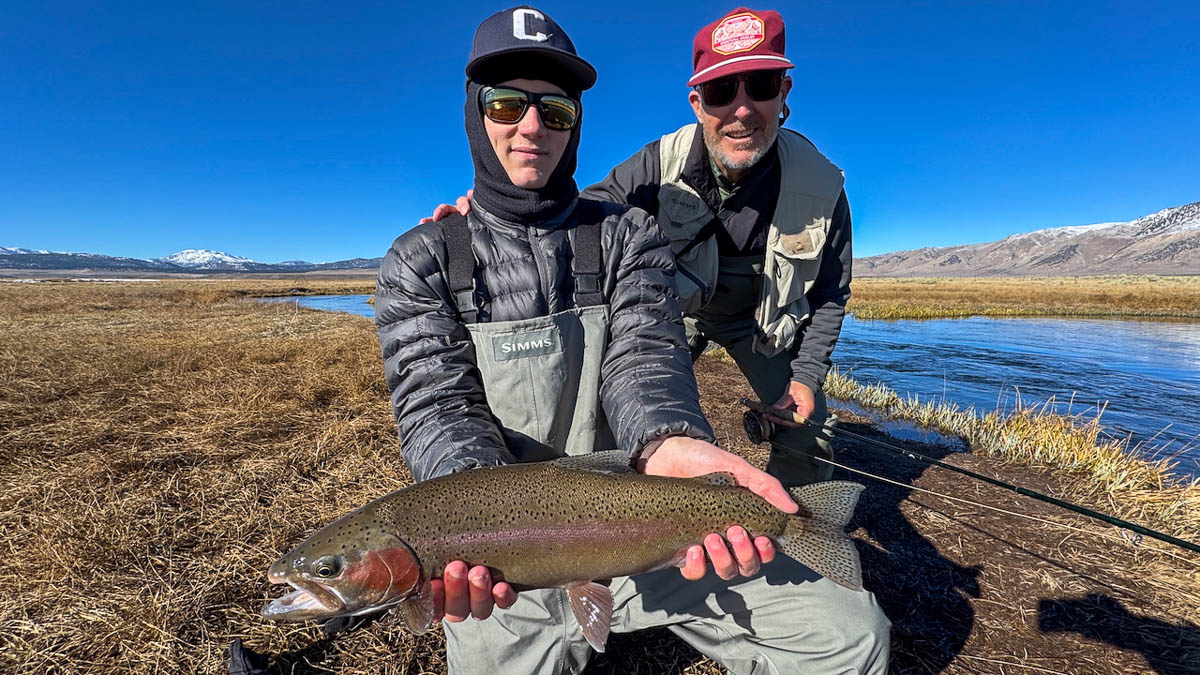 A fly fisheman holding a large rainbow trout on the Upper Owens River near Mammoth Lakes, CA