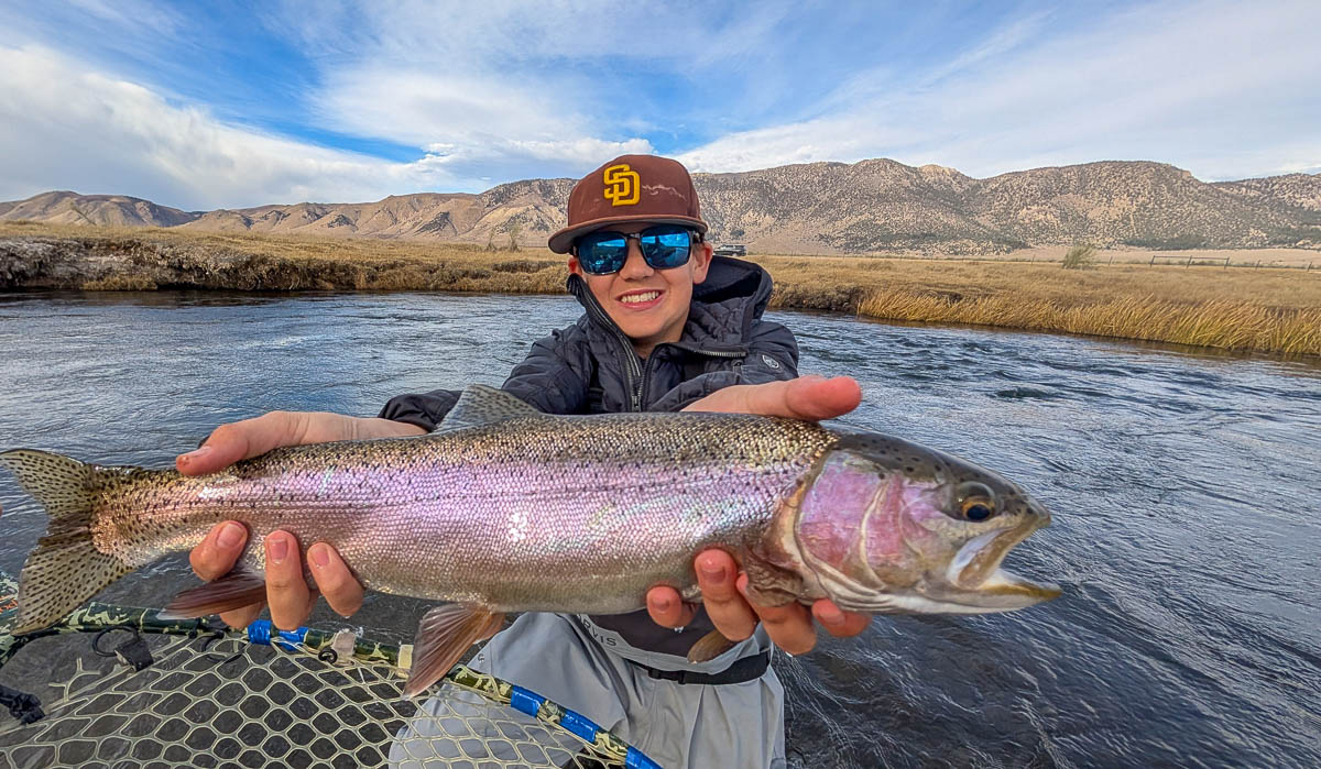 A fly fisheman holding a large rainbow trout on the Upper Owens River near Mammoth Lakes, CA