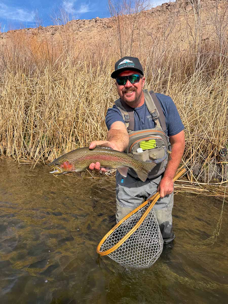 A fly fisheman holding a large rainbow trout on the Upper Lower River near Mammoth Lakes, CA