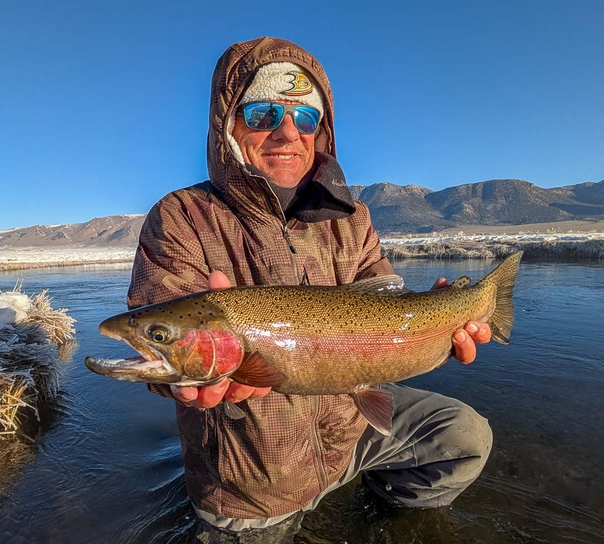 A fly fisheman holding a large rainbow trout on the Upper Owens River near Mammoth Lakes, CA