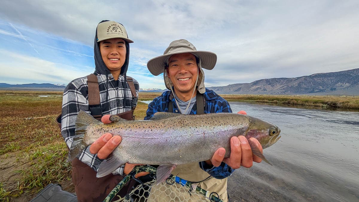 A fly fisherman holding a large rainbow trout on the Upper Owens River near Mammoth Lakes, CA