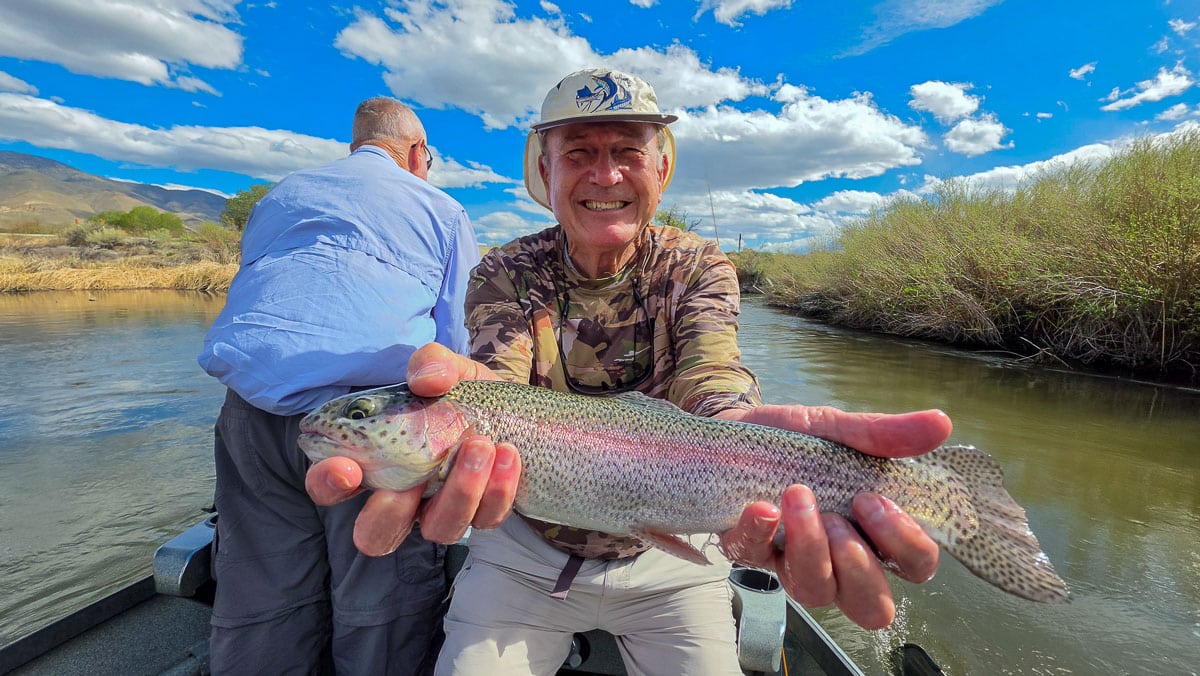 A fly fisherman holding a large rainbow trout on the Lower Owens River near Bishop, CA