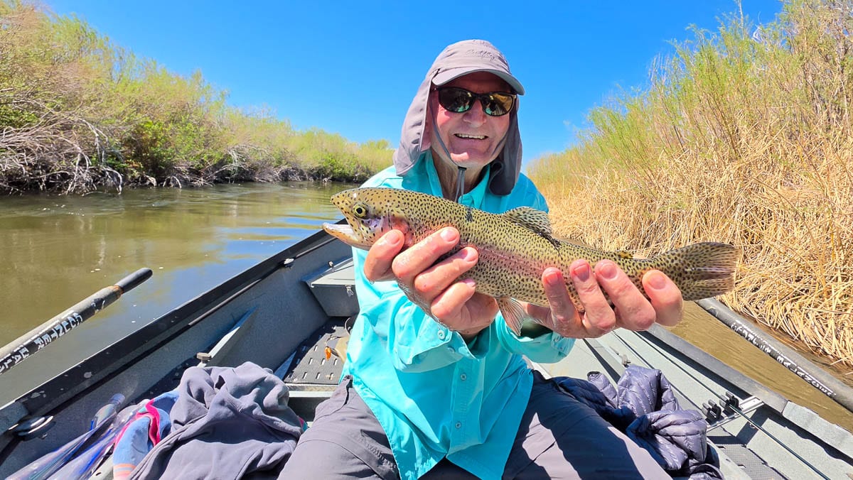 A fly fisherman holding a large rainbow trout on the Lower Owens River near Bishop, CA