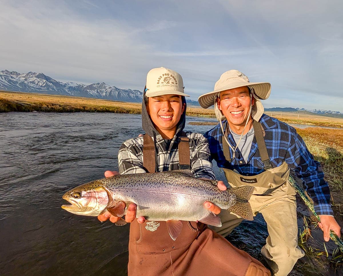 A fly fisherman holding a large rainbow trout on the Upper Owens River near Mammoth Lakes, CA