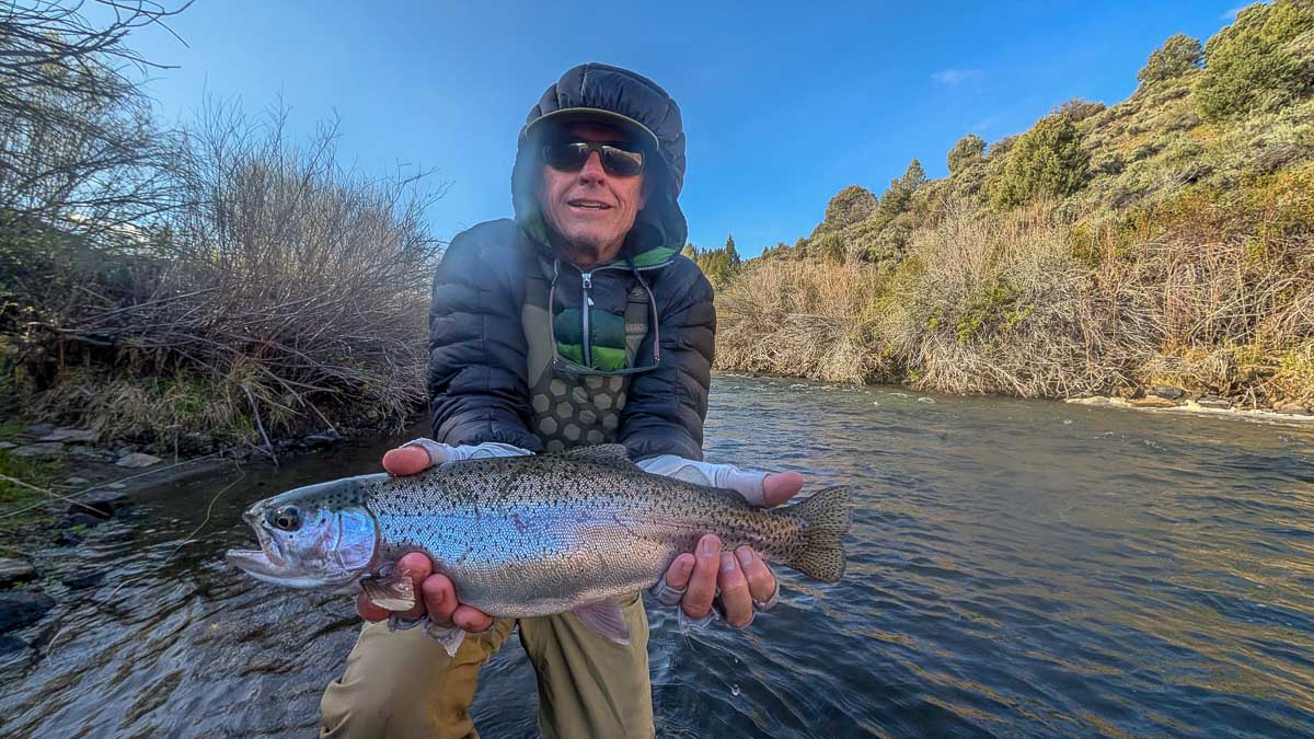 A fly fisherman holding a large rainbow trout on the Upper Owens River near Mammoth Lakes, CA
