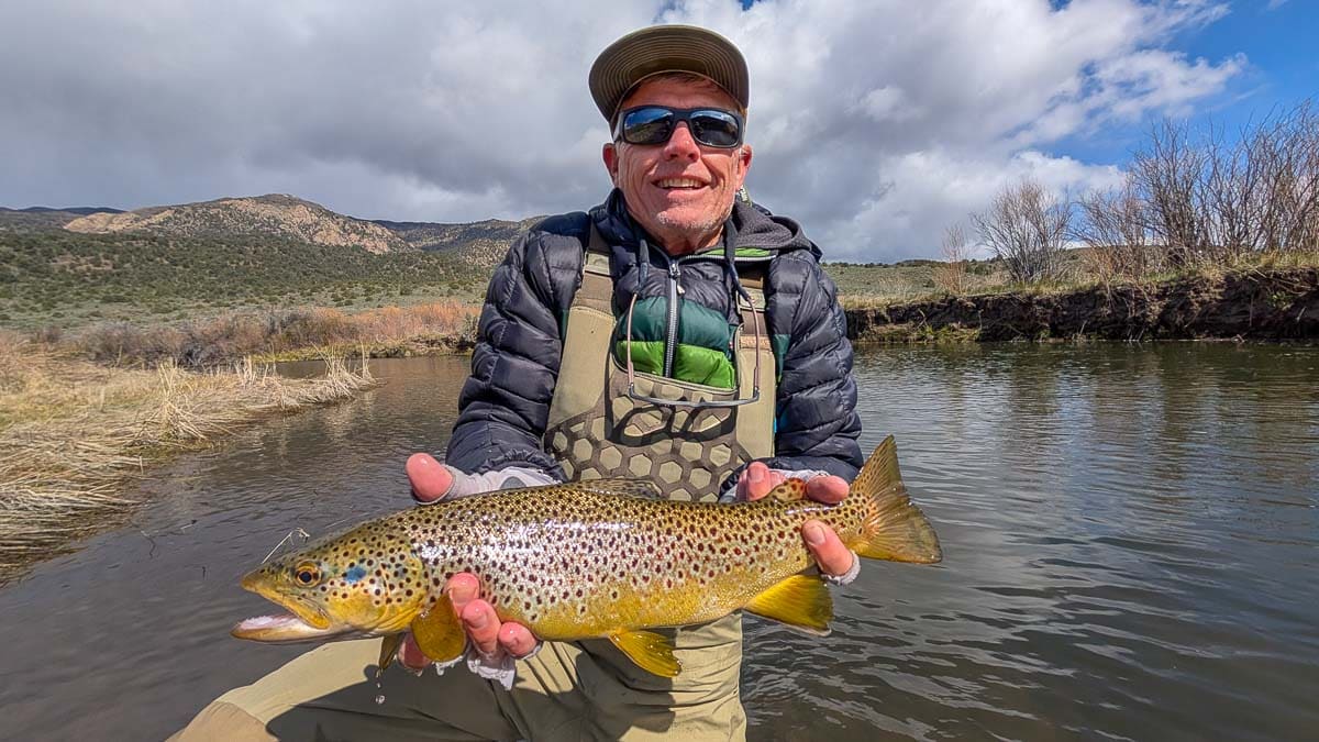 A fly fisherman holding a rainbow trout on the Lower Owens River near Bishop, CA