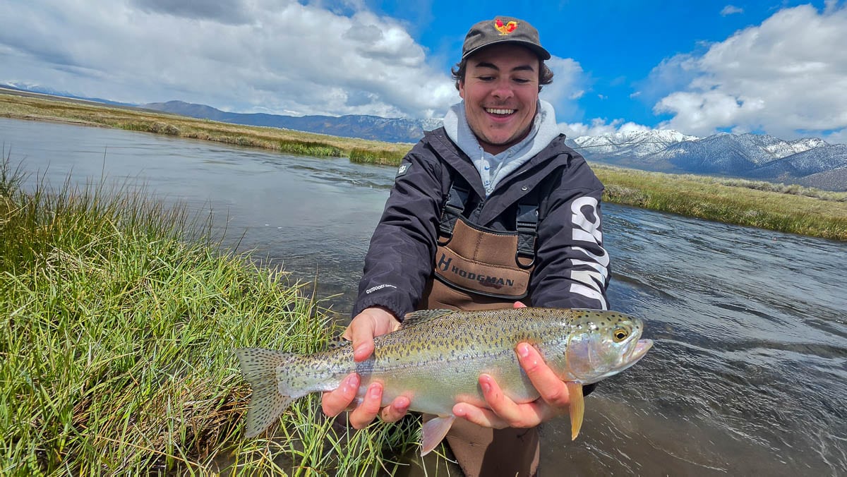 A fly fisherman holding a large brown trout on the Lower Owens River near Bishop, CA