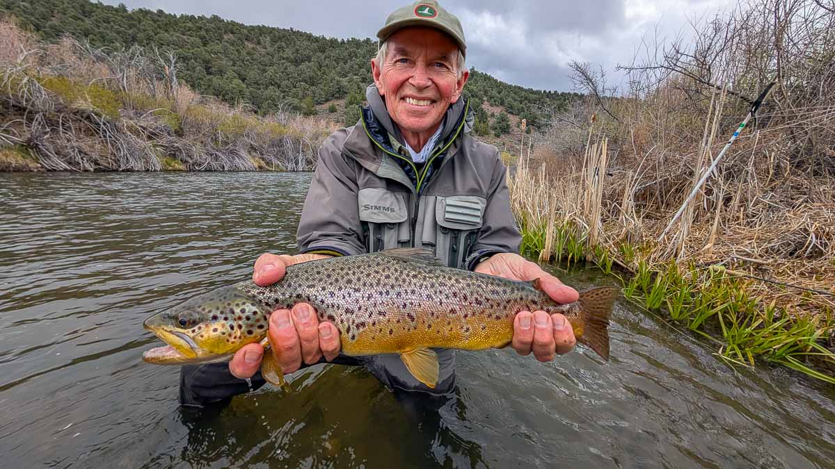 A fly fisherman holding a large rainbow trout on the Upper Owens River near Mammoth Lakes, CA