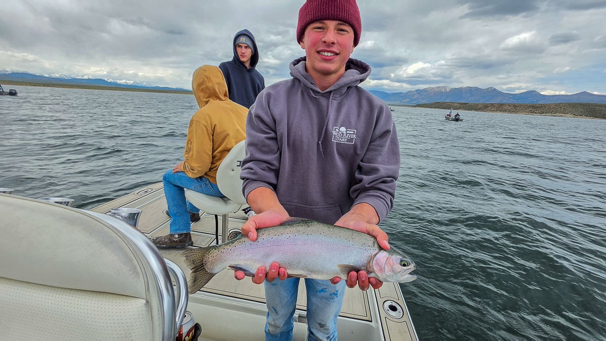 A fly fisherman holding a large rainbow trout on the Upper Owens River near Mammoth Lakes, CA