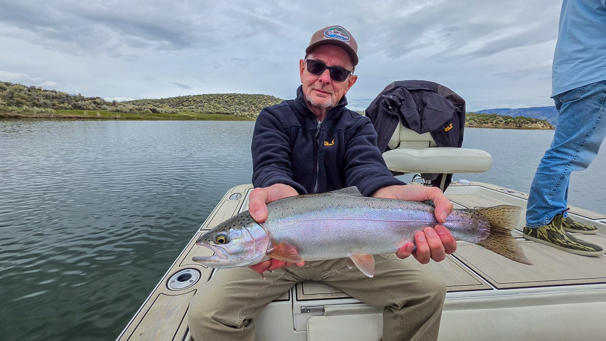 A fly fisherman holding a large rainbow trout on the Upper Owens River near Mammoth Lakes, CA