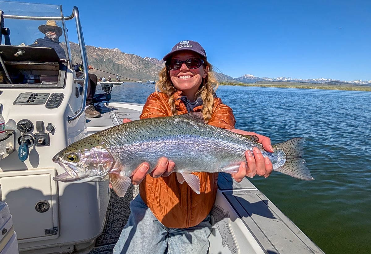 A fly fisherman holding a large rainbow trout on the Upper Owens River near Mammoth Lakes, CA