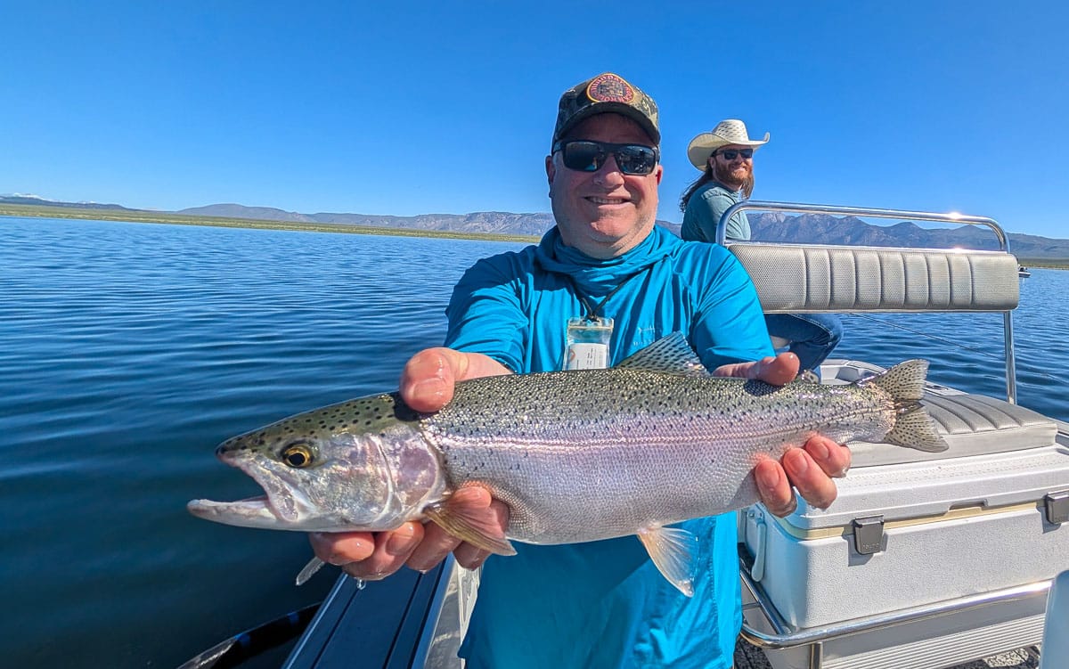 A fly fisherman holding a rainbow trout on the Lower Owens River near Bishop, CA