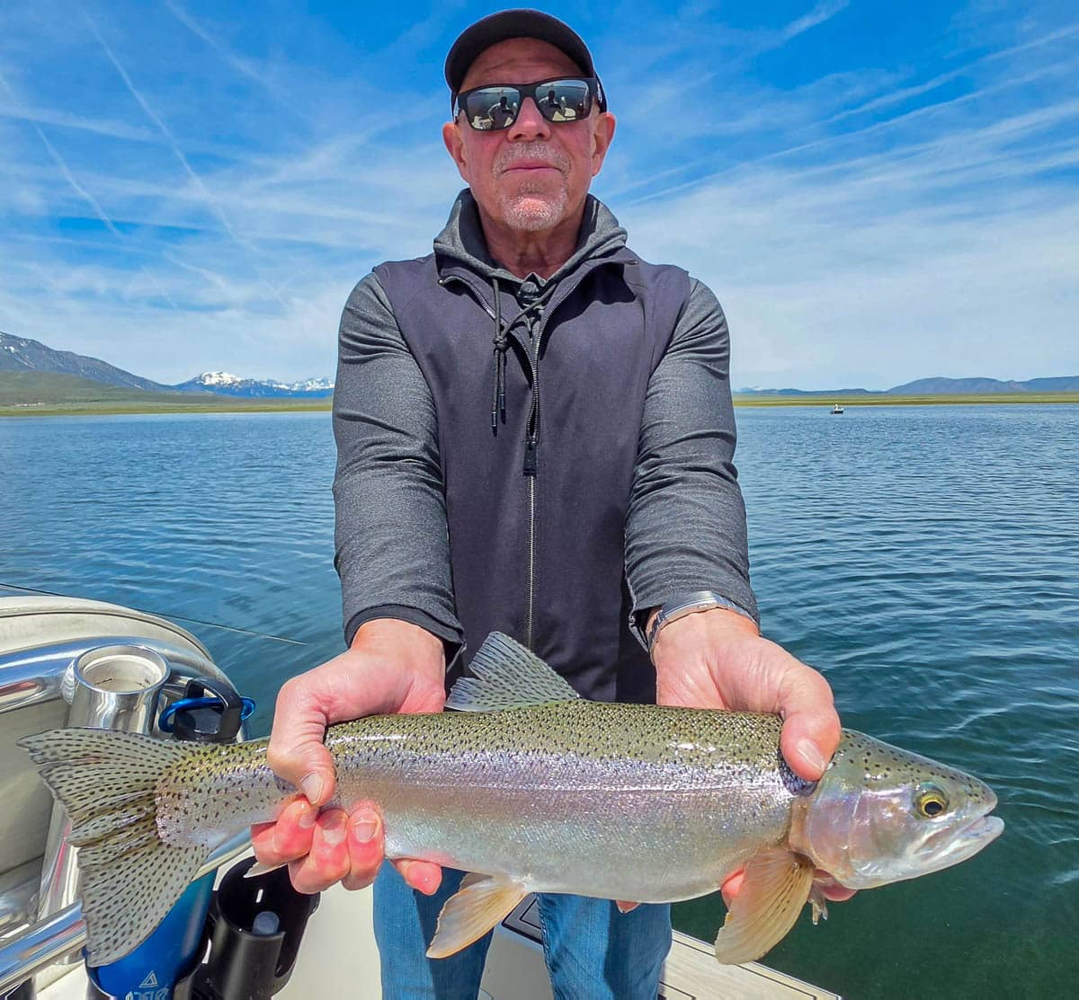 A fly fisherman holding a large rainbow trout on the Upper Owens River near Mammoth Lakes, CA