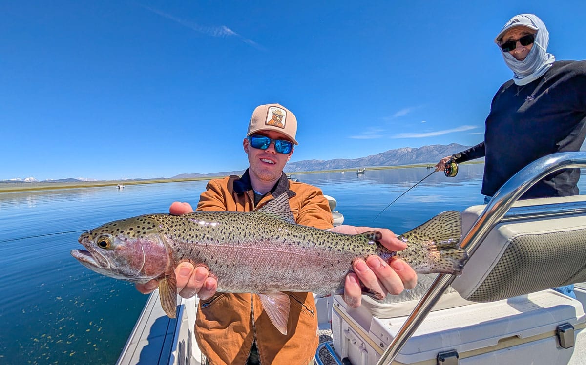 A fly fisherman holding a large rainbow trout on the Upper Owens River near Mammoth Lakes, CA