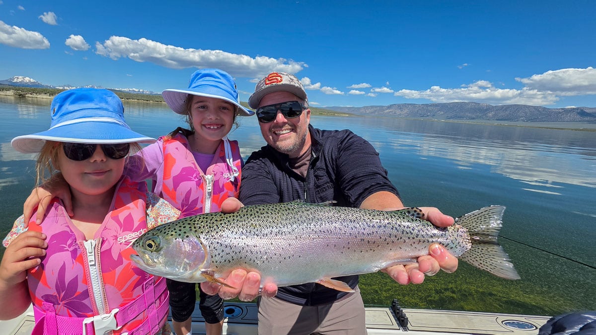 A fly fisherman holding a large rainbow trout on the Upper Owens River near Mammoth Lakes, CA