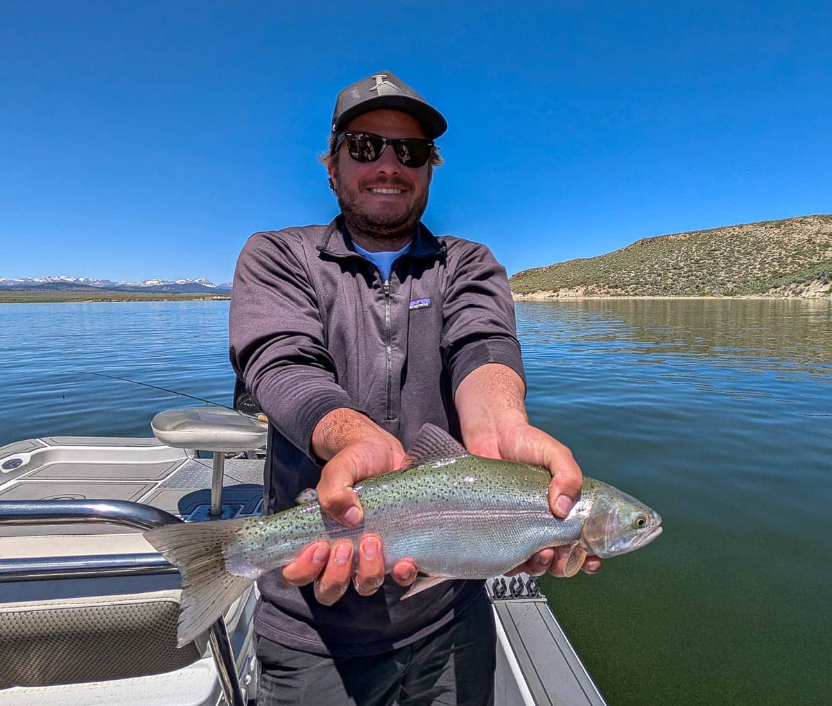 A fly fisherman holding a large rainbow trout on the Upper Owens River near Mammoth Lakes, CA