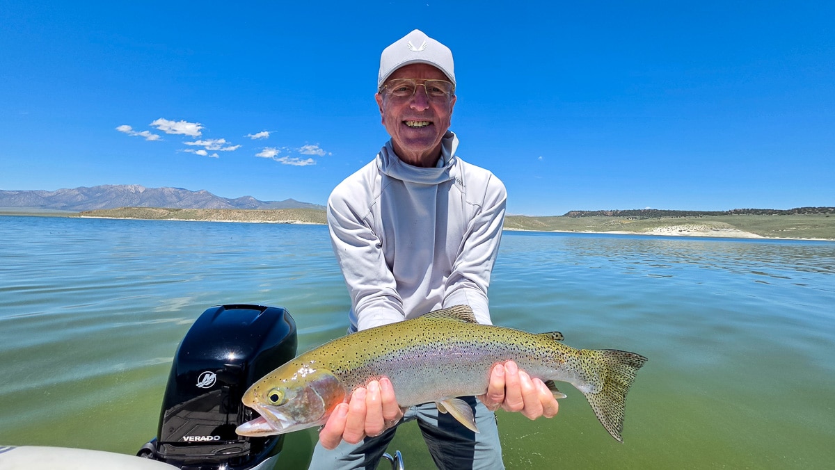 A fly fisherman holding a rainbow trout on the Lower Owens River near Bishop, CA