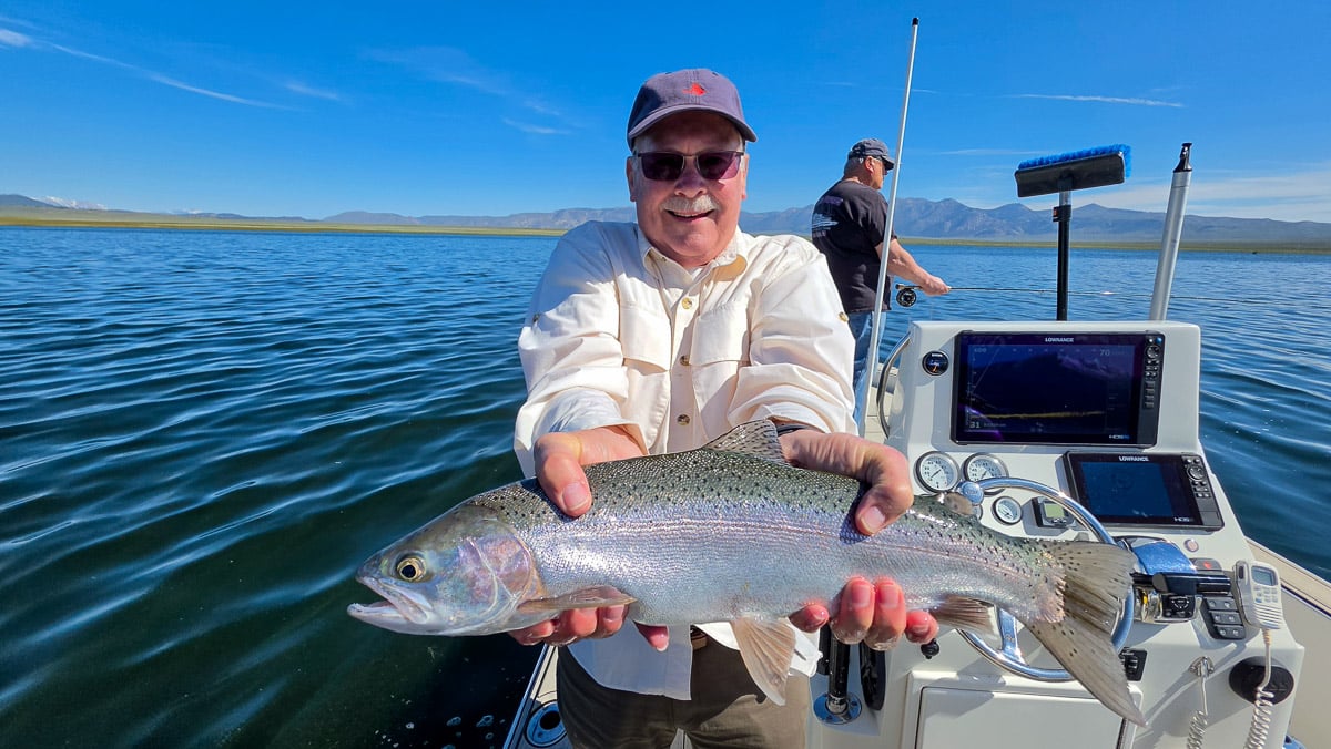 A fly fisherman holding a large rainbow trout on the Upper Owens River near Mammoth Lakes, CA