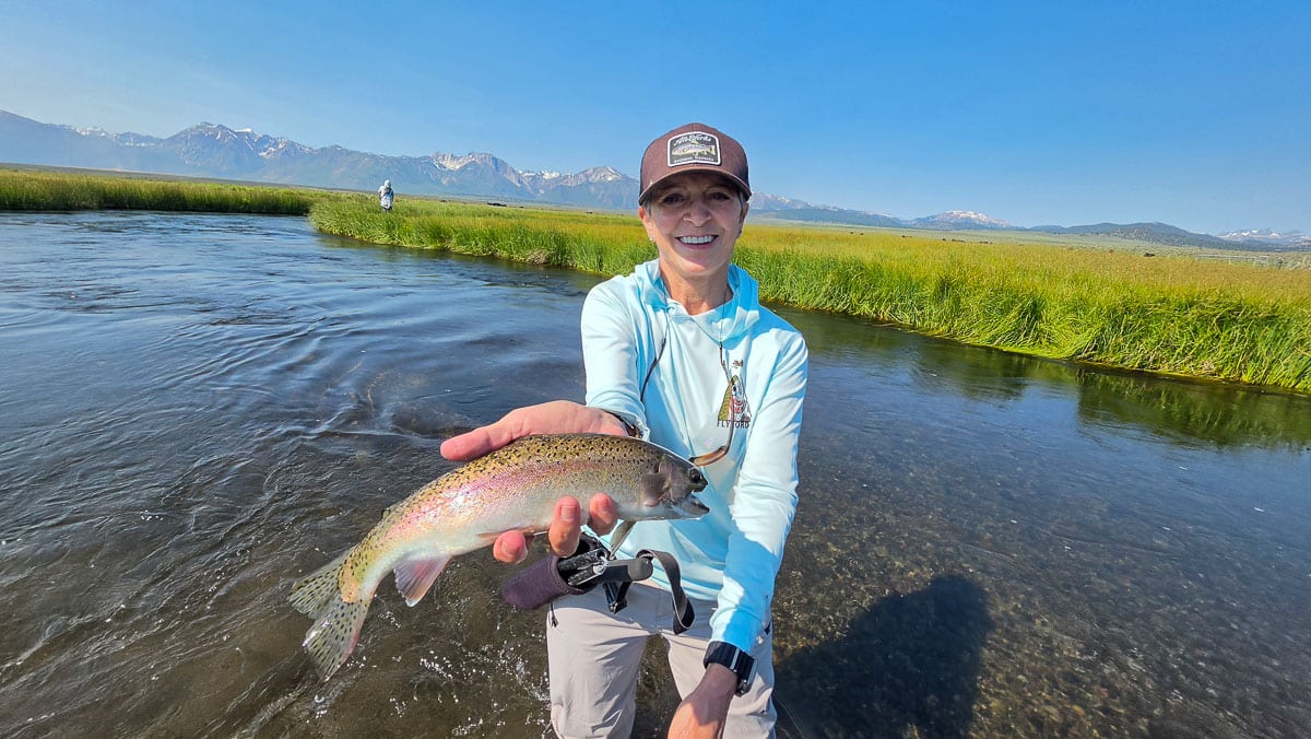 A fly fisherman holding a large rainbow trout on the Upper Owens River near Mammoth Lakes, CA