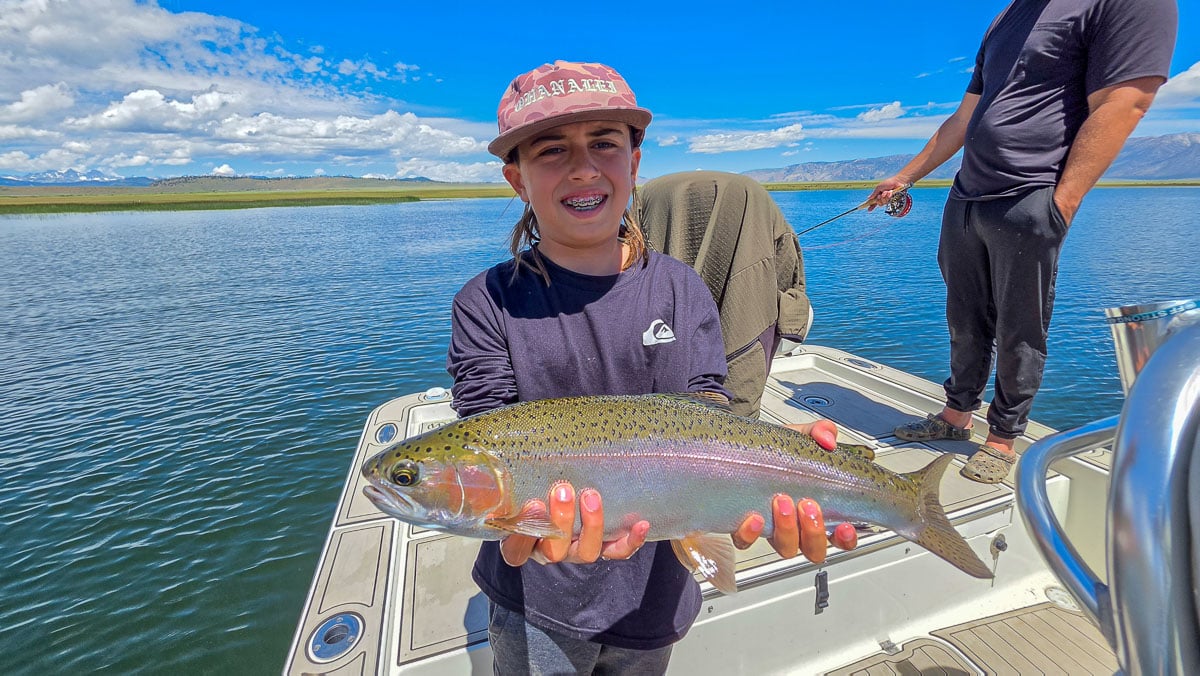 A fly fisherman holding a large rainbow trout on the Upper Owens River near Mammoth Lakes, CA