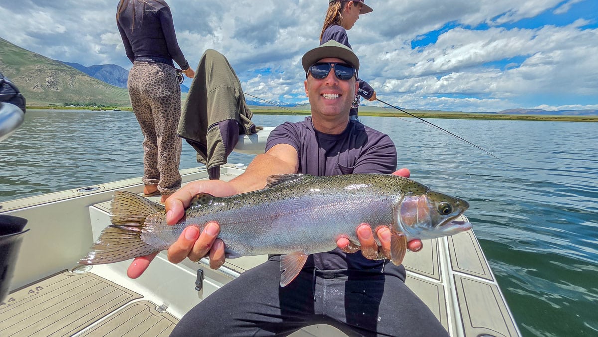 A fly fisherman holding a large rainbow trout on the Upper Owens River near Mammoth Lakes, CA