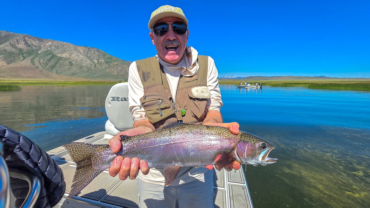 A fly fisherman holding a large brown trout on the Lower Owens River near Bishop, CA