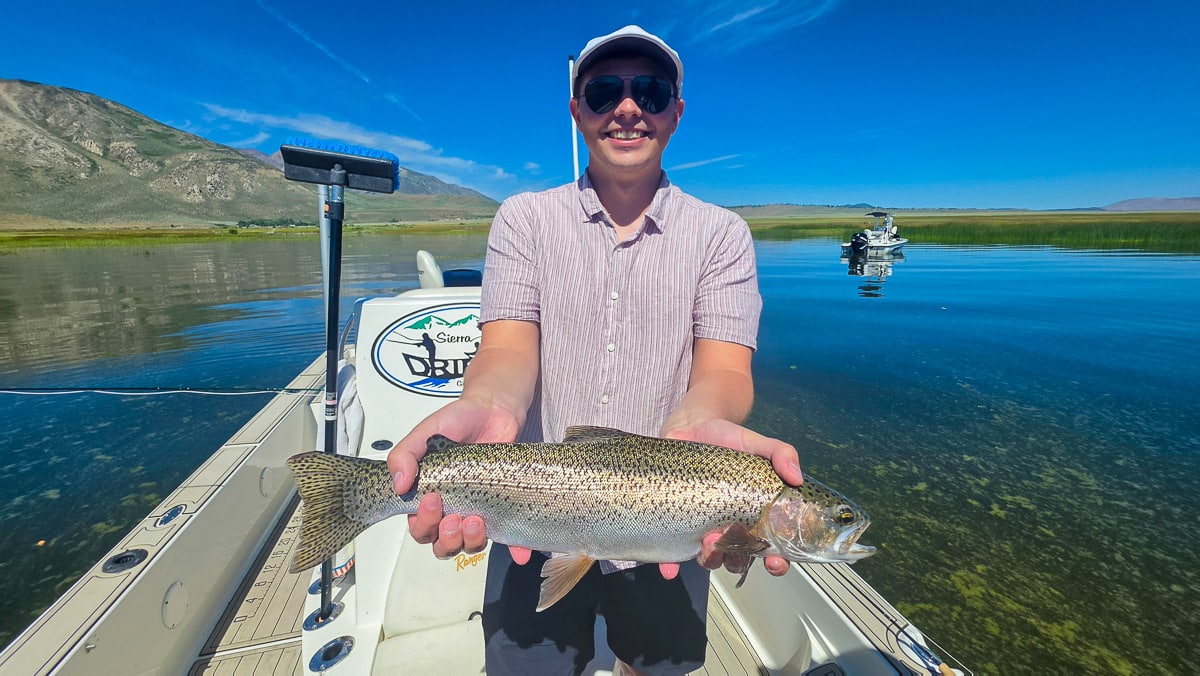 A fly fisherman holding a rainbow trout on the Lower Owens River near Bishop, CA