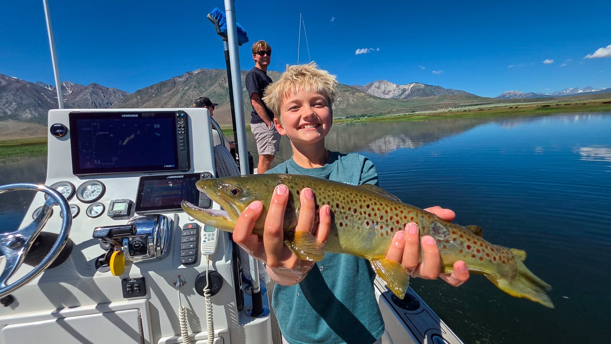 A fly fisherman holding a large rainbow trout on the Upper Owens River near Mammoth Lakes, CA