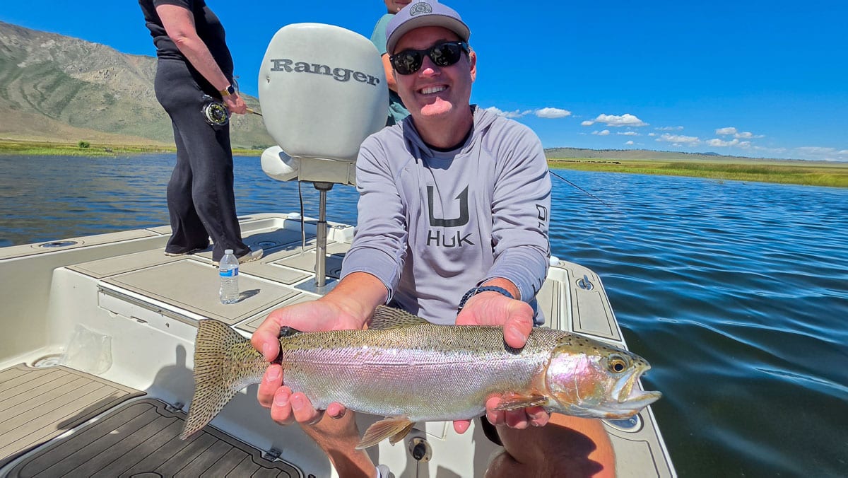 A fly fisherman holding a large rainbow trout on the Upper Owens River near Mammoth Lakes, CA