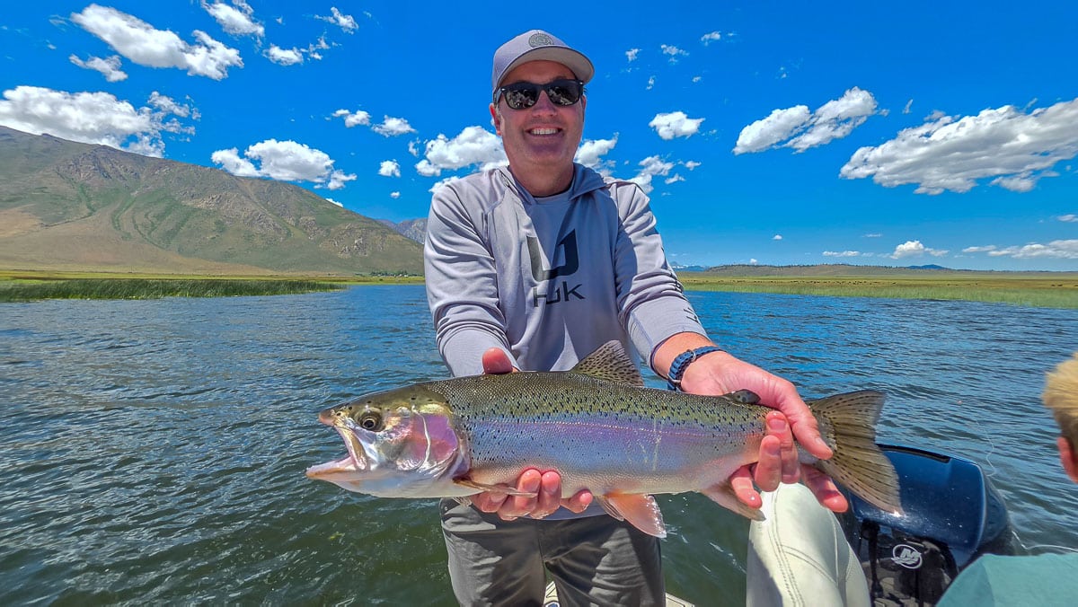 A fly fisherman holding a large rainbow trout on the Upper Owens River near Mammoth Lakes, CA