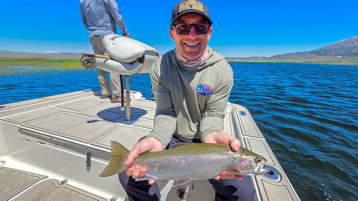 A fly fisherman holding a large rainbow trout on the Upper Owens River near Mammoth Lakes, CA