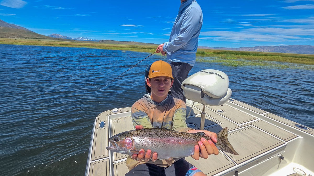 A fly fisherman holding a large rainbow trout on the Upper Owens River near Mammoth Lakes, CA