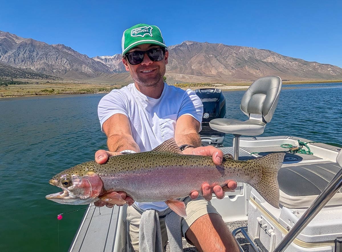 A fly fisherman holding a large rainbow trout on the Upper Owens River near Mammoth Lakes, CA