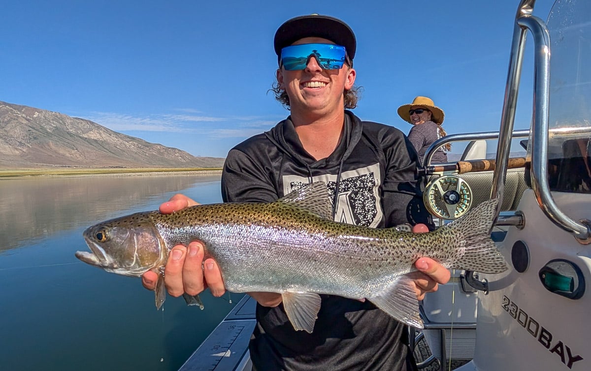 A fly fisherman holding a large rainbow trout on the Upper Owens River near Mammoth Lakes, CA