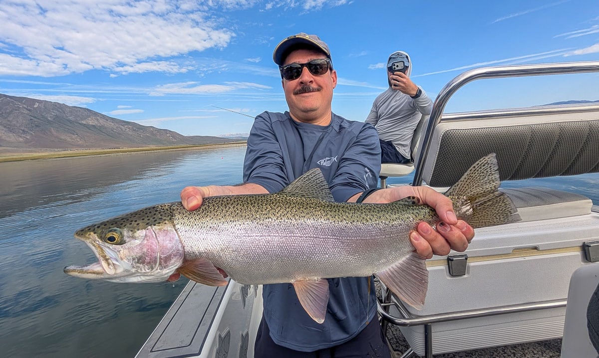 A fly fisherman holding a large rainbow trout on the Upper Owens River near Mammoth Lakes, CA