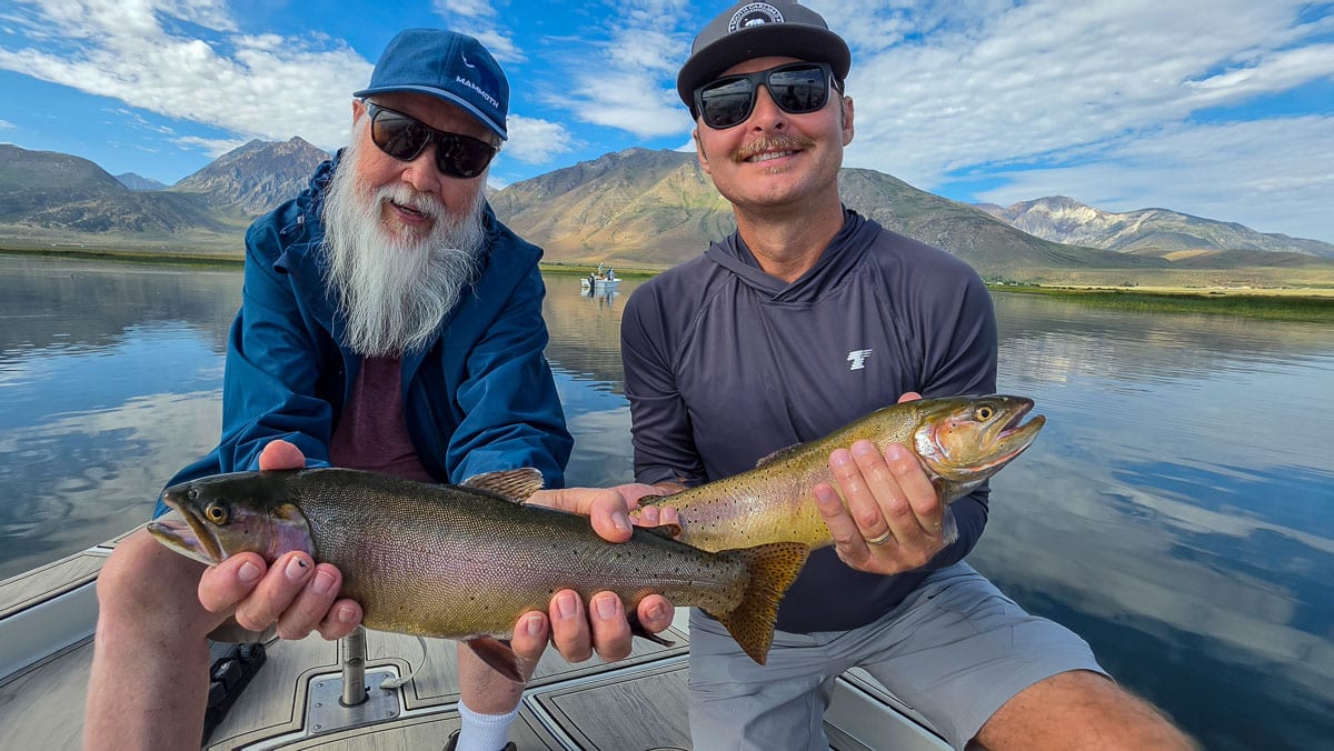 A fly fisherman holding a large rainbow trout on the Upper Owens River near Mammoth Lakes, CA