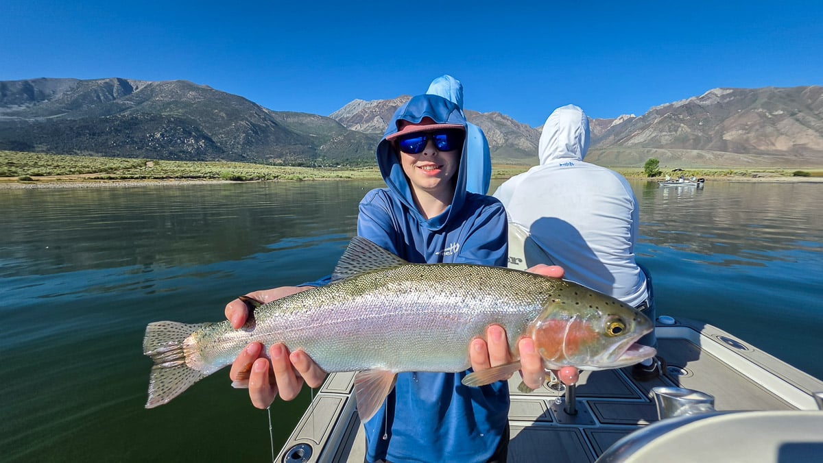 A fly fisherman holding a large rainbow trout on the Hot Creek River near Mammoth Lakes, CA