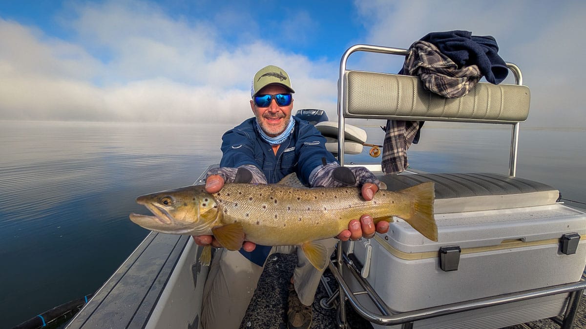A fly fisherman holding a large rainbow trout on the Upper Owens River near Mammoth Lakes, CA