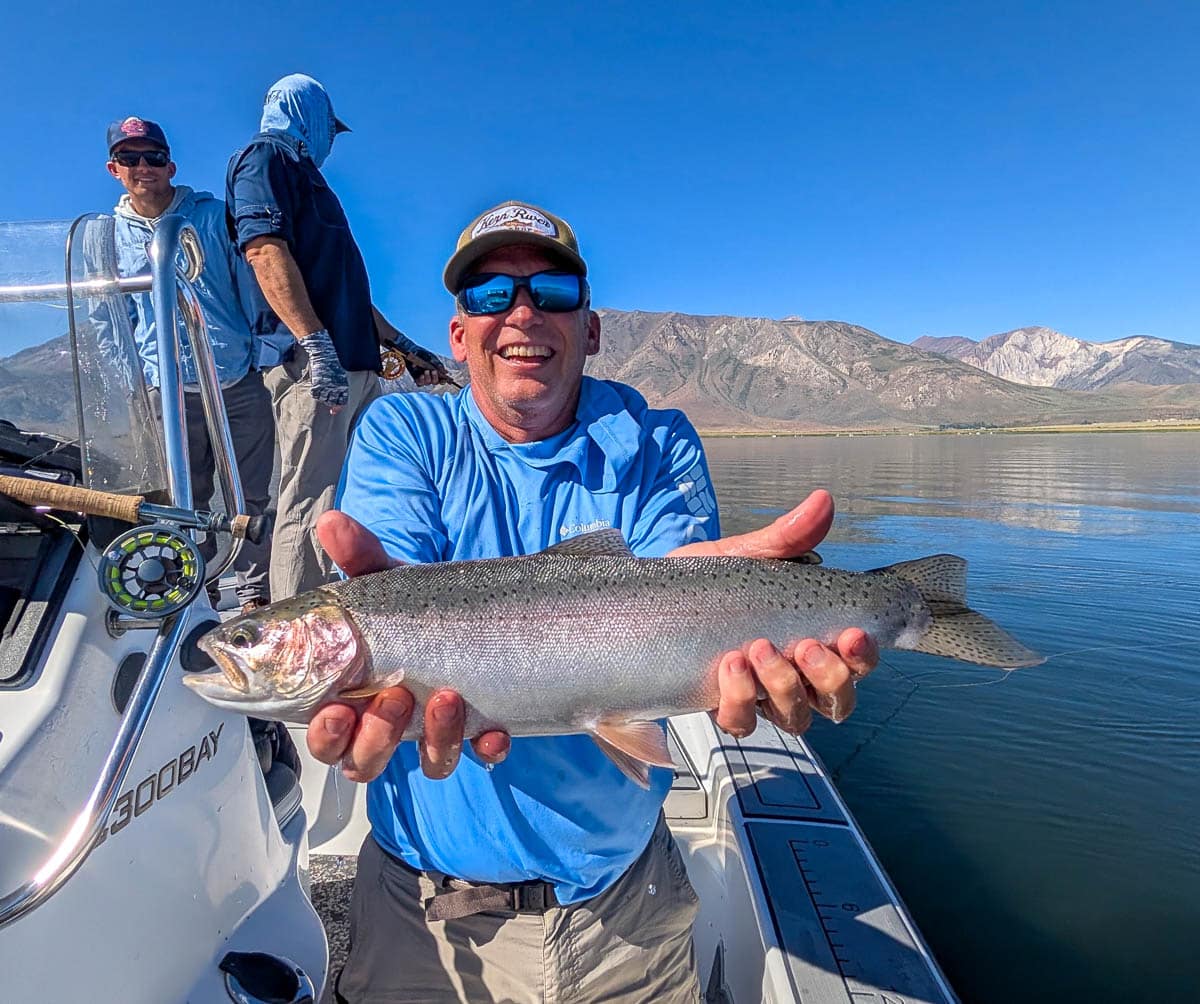 A fly fisherman holding a large rainbow trout on the Upper Owens River near Mammoth Lakes, CA
