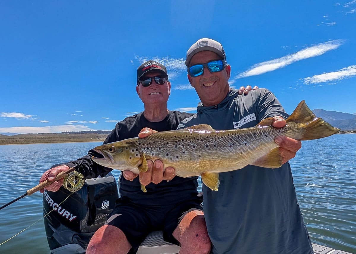A fly fisherman holding a large rainbow trout on the Upper Owens River near Mammoth Lakes, CA