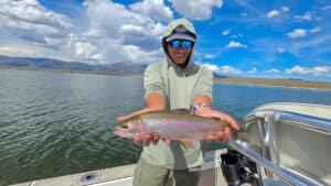 A fly fisherman holding a large rainbow trout in a boat on Crowley Lake near Mammoth Lakes, CA