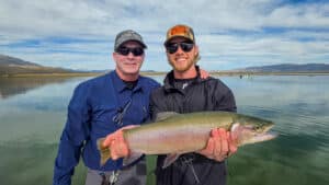 A fly fisherman holding a large cuthhroat trout in a boat on Crowley Lake near Mammoth Lakes, CA