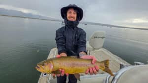 A fly fisherman holding a large cuthhroat trout in a boat on Crowley Lake near Mammoth Lakes, CA