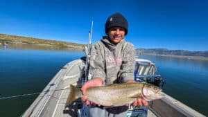 A fly fisherman holding a large cuthhroat trout in a boat on Crowley Lake near Mammoth Lakes, CA
