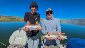 A pair of fly fisherman holding a large cuthhroat trout and rainbow trout in a boat on Crowley Lake near Mammoth Lakes, CA
