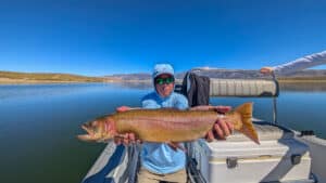 A fly fisherman holding a large cuthhroat trout in a boat on Crowley Lake near Mammoth Lakes, CA